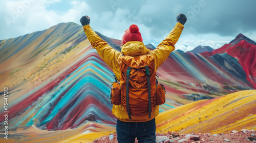 a man tourist is standing with both hands raised After successfully conquering the peak , on top of a mountain,Vinicunca Rainbow Mountain,generative ai photo