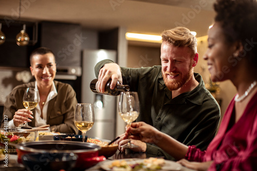 Friends drinking wine during dinner party at home photo