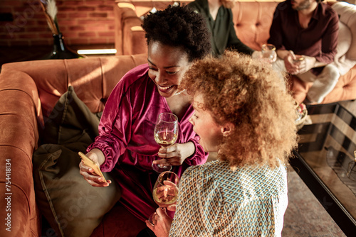 Two female friends having wine together at home party