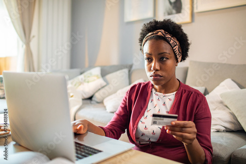 Stressed woman using credit card on laptop at home photo