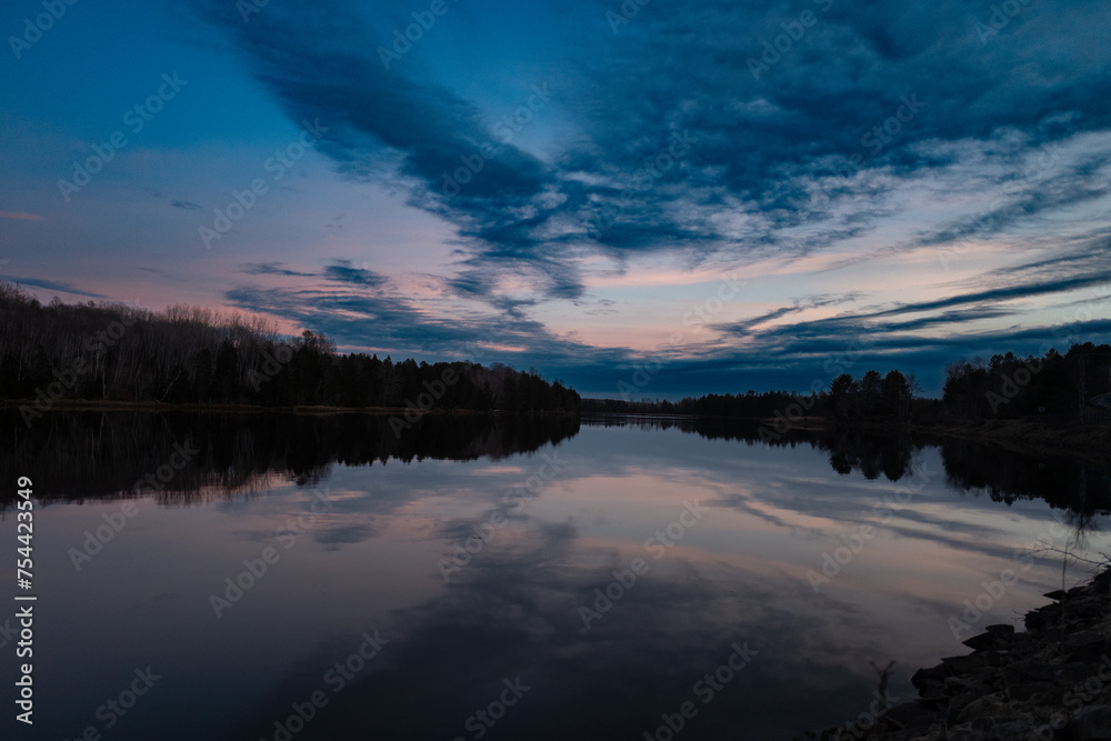 a beautiful lake during sunset with lots of clouds in the sky
