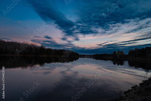 a beautiful lake during sunset with lots of clouds in the sky