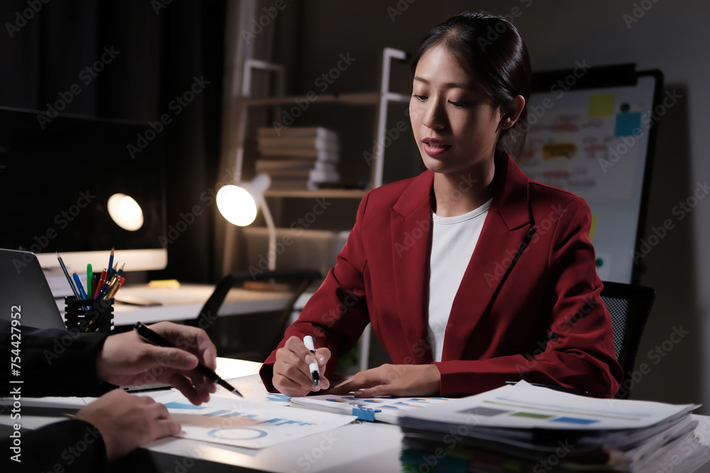 Fototapeta premium A woman in a red jacket is sitting at a desk with a man