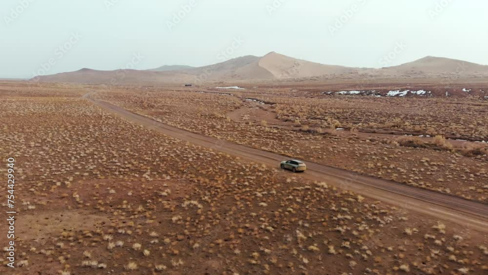 A car driving fast in a deserted area. Cold season, remnants of snow. Arid area with sparse vegetation. Altyn-Emel National Park A car driving fast in a deserted area. Cold season, remnants of snow. Arid area with sparse vegetation. Altyn-Emel National Park