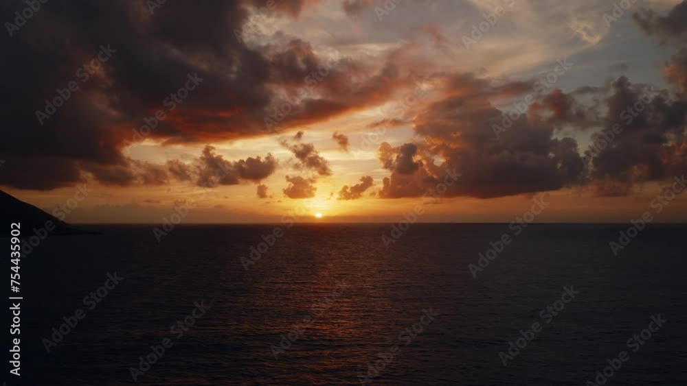 Aerial horizon view above the sea during a scenic sunset with thick clouds in the golden sky Aerial horizon view above the sea during a scenic sunset with thick clouds in the golden sky