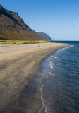 Girl walking alone on sandy beach close to Önundarfjörður Pier in Westfjords, Iceland. Beautiful nature and travel destination