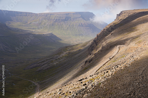 Winding gravel road leading from Bolafjall mountain to Bolungarvík town in Westfjords, Iceland