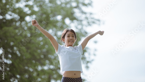 Portrait of happy Asian girl with arms outstretched in the park