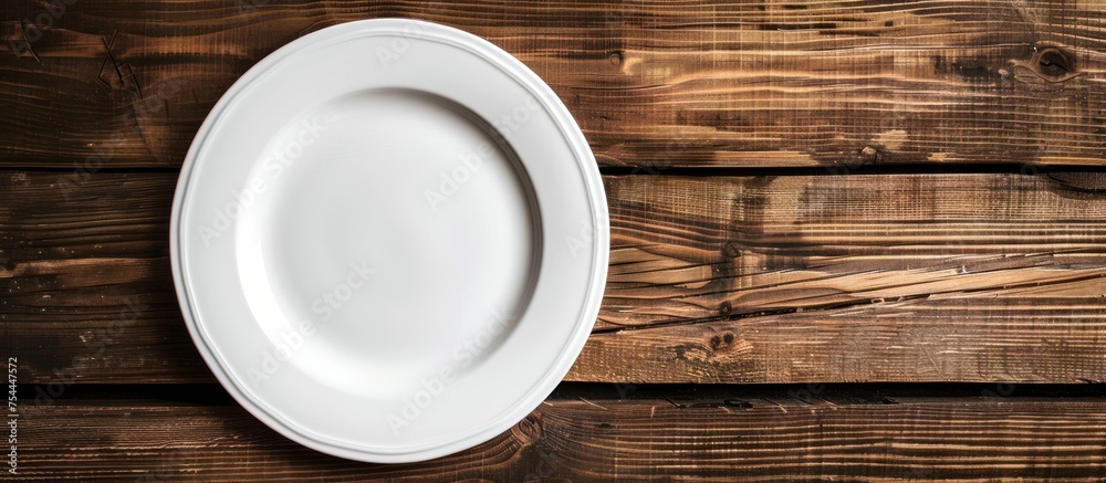 A white plate rests on a wooden table surface, creating a simple and elegant setup. A white plate rests on a wooden table surface, creating a simple and elegant setup.