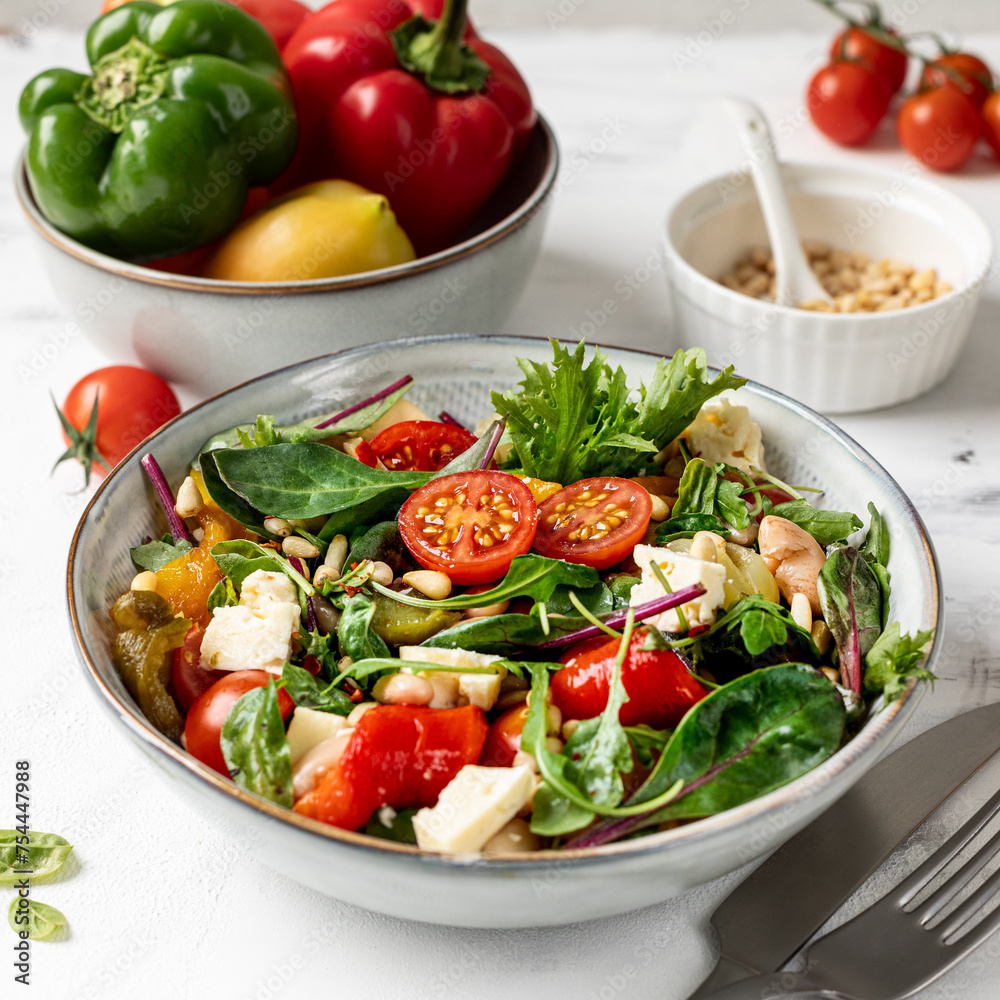 A plate with baked peppers, beans and tomatoes on a white background. A plate with baked peppers, beans and tomatoes on a white background.