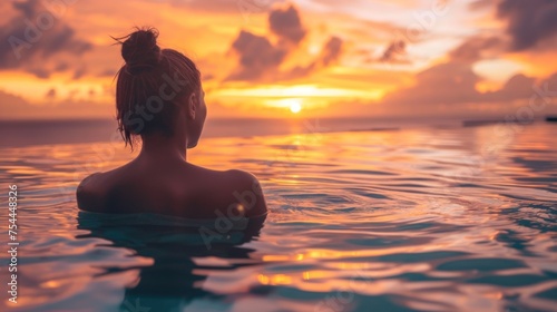 A woman is in the water  looking at the sun. The water is calm and the sky is orange. sunset background