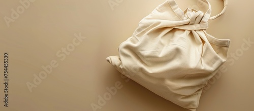 A white canvas bag is seen on top of a sturdy wall, creating a simple yet striking contrast in color and texture.