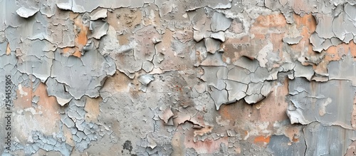 Detailed view of a weathered concrete wall with peeling layers of paint, revealing the rough texture of the surface underneath. photo