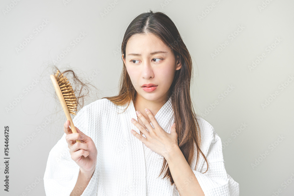 Serious asian young woman holding brush holding comb, hairbrush with fall black hair from scalp after brushing, looking on hand worry about balding. Health care, beauty treatment, hair loss problem. Serious asian young woman holding brush holding comb, hairbrush with fall black hair from scalp after brushing, looking on hand worry about balding. Health care, beauty treatment, hair loss problem.