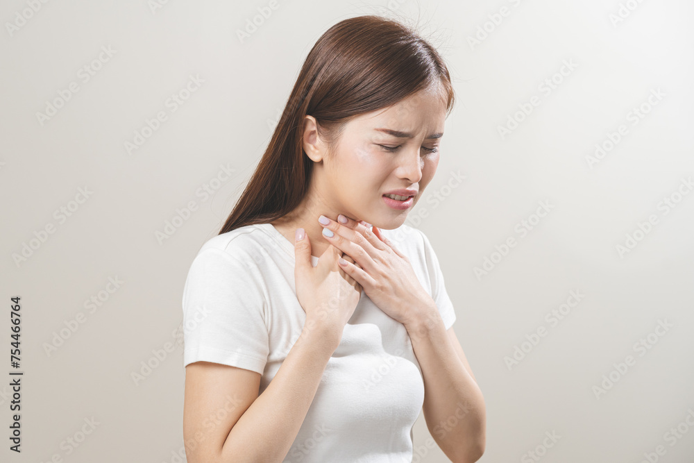 Sickness in inflaming asian young woman, girl use hand check self touch at sore throat, pain thyroid gland on neck or disease reflux, acid of suffer people on wall background. Medical and healthcare. Sickness in inflaming asian young woman, girl use hand check self touch at sore throat, pain thyroid gland on neck or disease reflux, acid of suffer people on wall background. Medical and healthcare.
