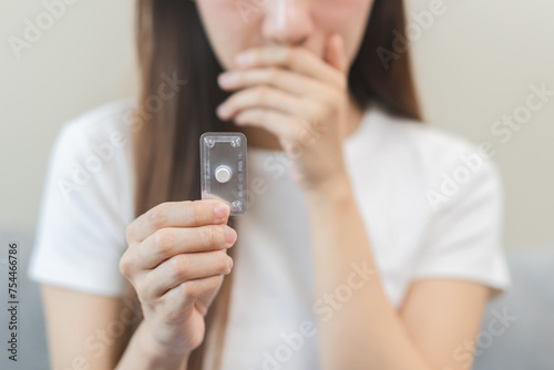 Fotografi Emergency contraception and pregnancy concept asian young woman hand holding birth control pills, hormonal oral contraceptive medicine at home, take pharmaceutical to prevention virus sex disease