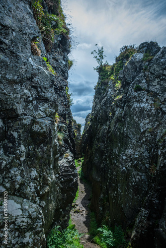 A large crack in the rocks like a crevasse or canyon, interesting rock formation, walking through a canyon in Scotland.  photo