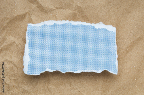 Blue paper  piece with ripped edge on brown paper background
