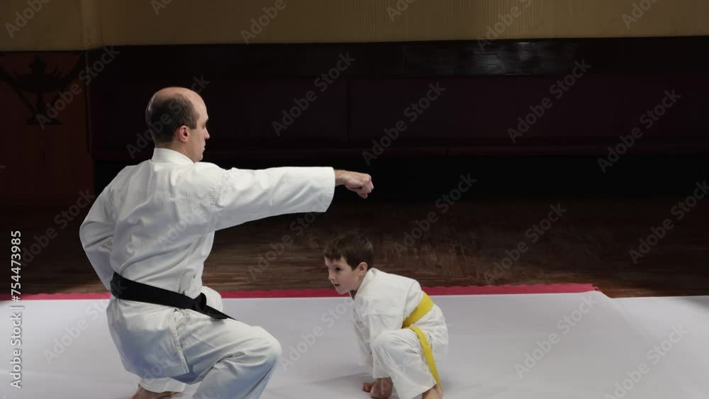 A coach and a little athlete perform a jump to a stand from a sitting position and punches A coach and a little athlete perform a jump to a stand from a sitting position and punches