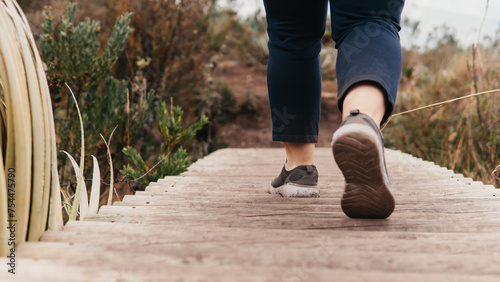 Close-up of a hiker's shoes on a wooden boardwalk amidst nature, symbolizing an active lifestyle