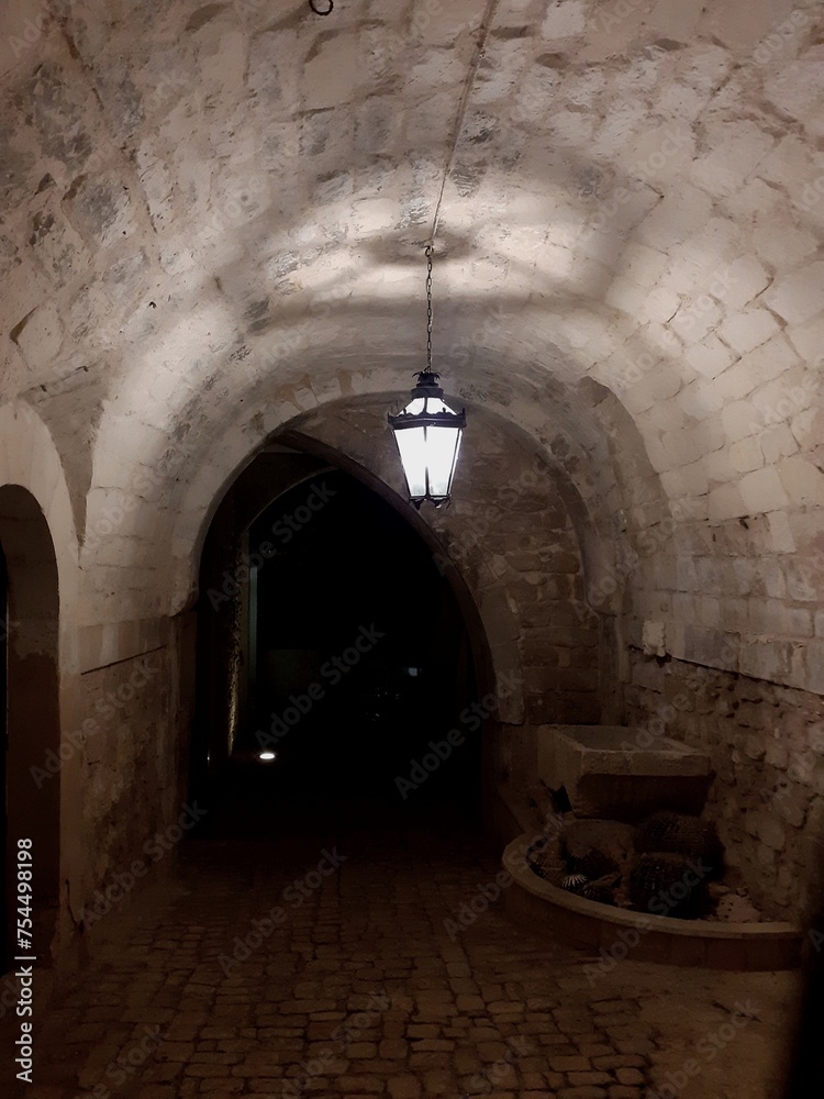 Fototapeta premium Vicolo con tunnel ad arco a Scicli, di notte, con lampione acceso.