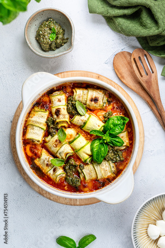 Italian zucchini rolls with cream cheese filling, baked in tomato sauce on a white background. photo