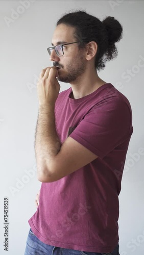 Medium shot of distracted young man biting his nails photo