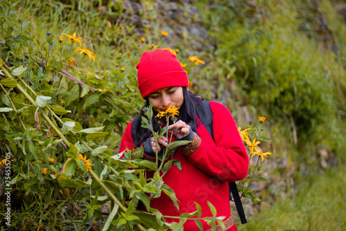 Atractiva mujer Explorando la belleza invernal,Chica con mochila roja admirando las flores amarillas en la sierra,estilo de vida photo