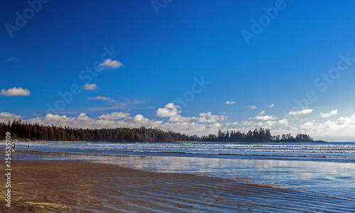 View of Long Beach, beautiful natural wide sandy beach. Blue water with light waves, people on the beach in Pacific Rim National Park, Vancouver Island, British Columbia, Canada
