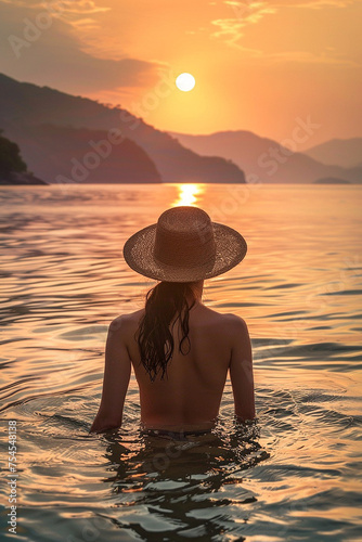 Back View of Unrecognizable Female Silhouette Standing in Rippling Sea Water Enjoying Sunset Over Mountains