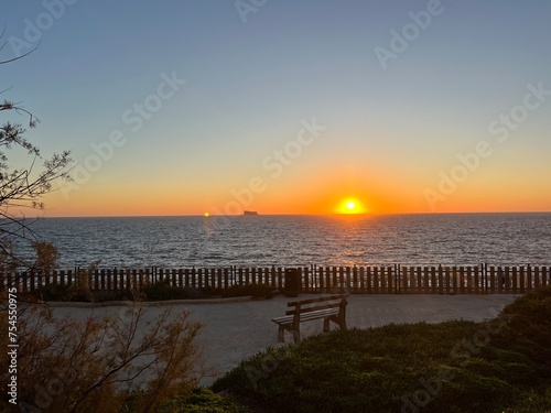 Sunset over the sea with a bench and a cruise ship in the background at Blue Harbour at Malta