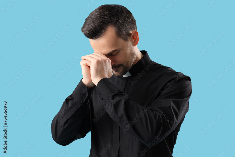 Portrait of male priest praying on blue background Portrait of male priest praying on blue background