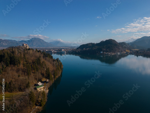 Aerial view of Lake Bled with the castle. Calm deep blue water surface with reflection. Panoramic view on a mountainous landscape in Slovenia.
