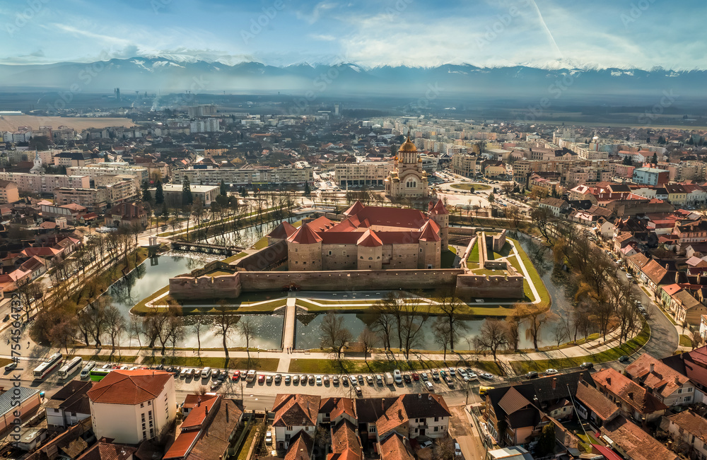 Aerial view with Fagaras Citadel Fortress, the Cathedral and the mountains in Romania