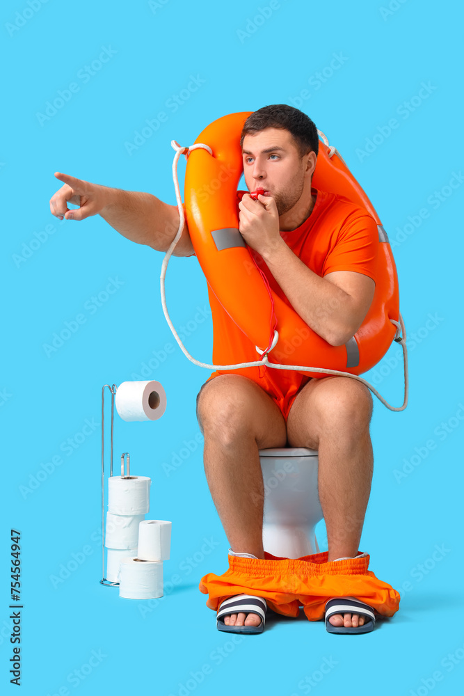 Male lifeguard with ring buoy whistling on toilet bowl against blue background - obrazy, fototapety, plakaty 