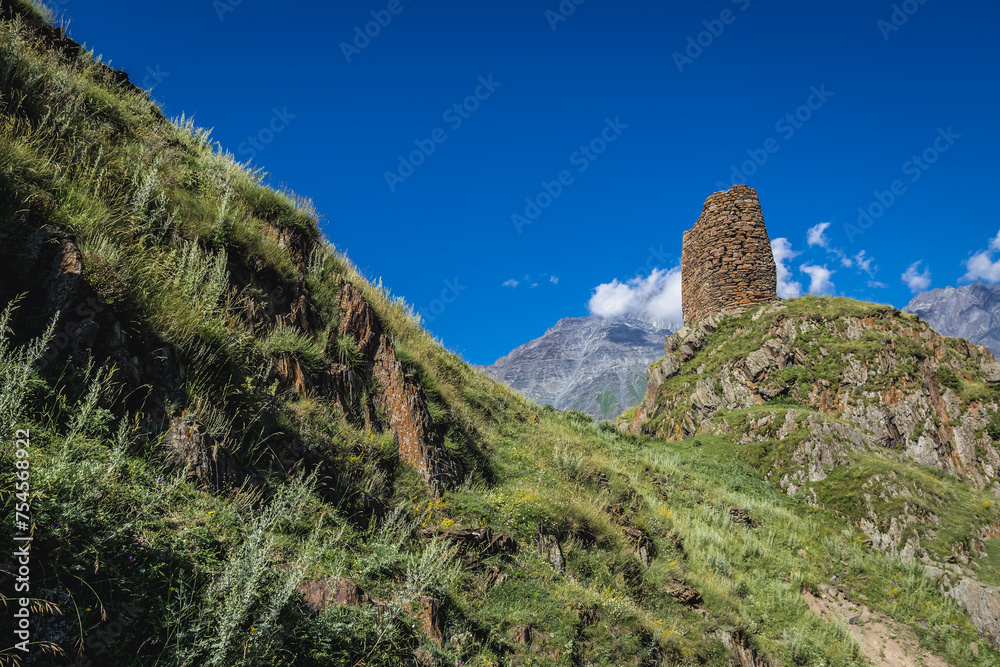 Old fortified tower near Gergeti village and Gergeti Holy Trinity Church in Caucasus Mountains, Georgia. Mount Shani on background