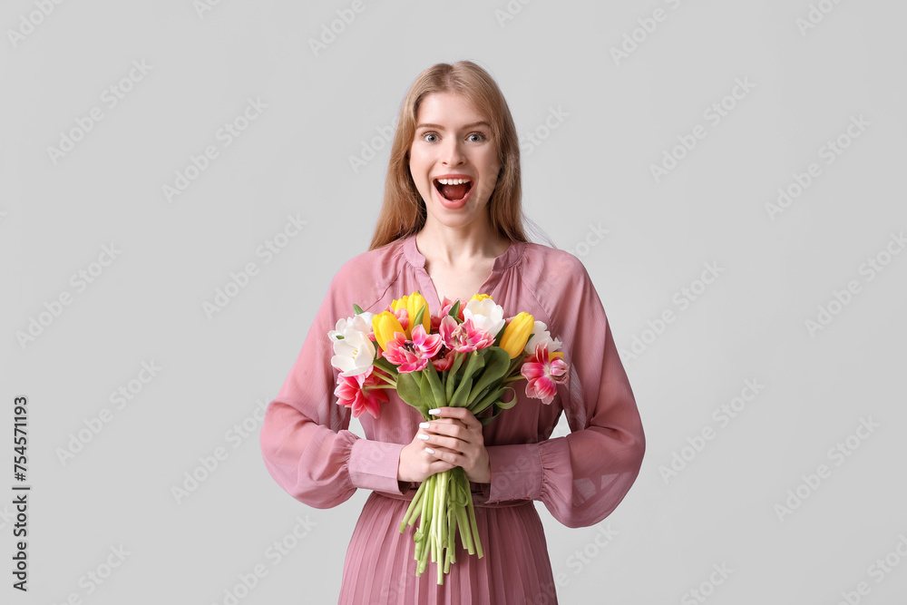 Surprised young woman with bouquet of beautiful tulips on grey background Surprised young woman with bouquet of beautiful tulips on grey background