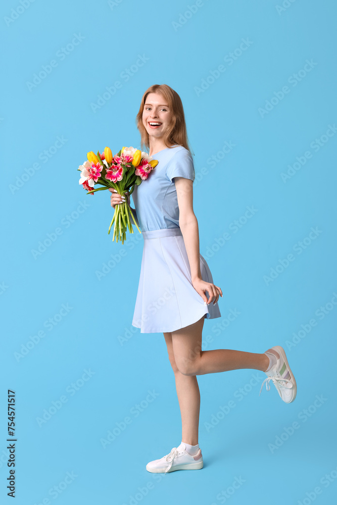 Happy young woman with bouquet of beautiful tulips on blue background