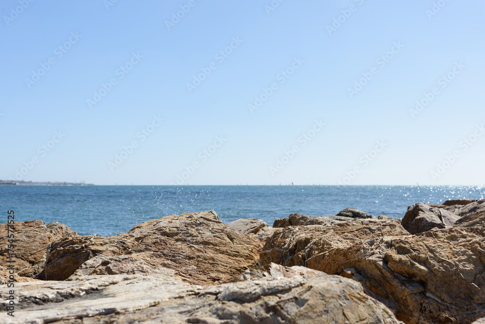 Seascape - huge stones of the coast in the foreground are covered by a sea wave