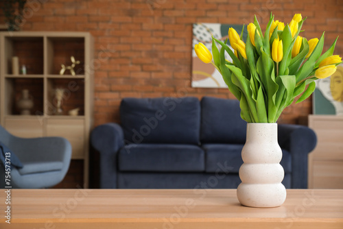 Beautiful tulips in vase on table in living room