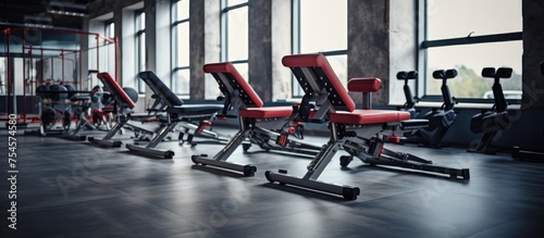 A row of various gym equipment such as treadmills, weight benches, and elliptical machines lined up in a bright and spacious gym.