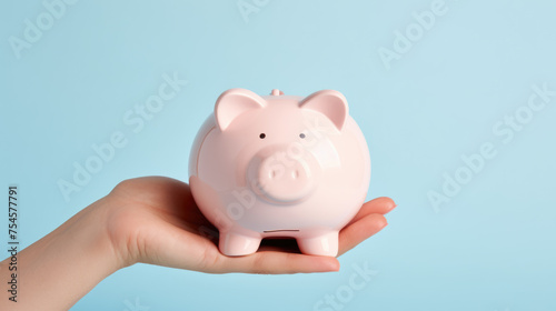 Hand holding a pink piggy bank, symbolizing personal savings and financial planning.
