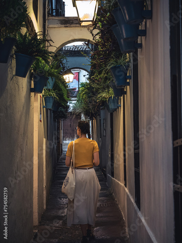 Young beautiful woman tourist walking down the Calleja de las Flores street in the evening photo