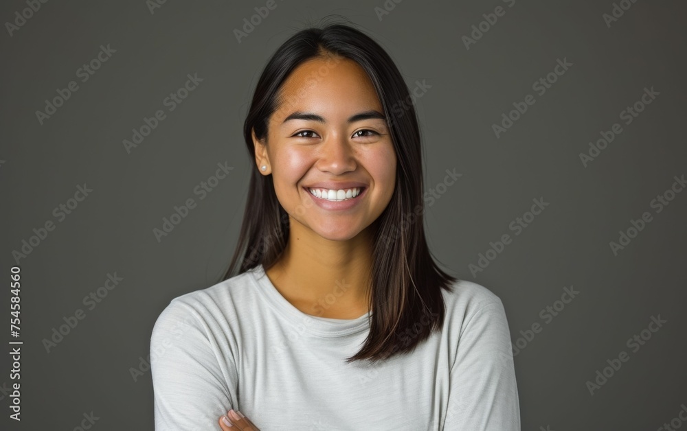A woman with long hair is smiling and posing for a picture. She is wearing a white shirt and has her arms crossed A woman with long hair is smiling and posing for a picture. She is wearing a white shirt and has her arms crossed
