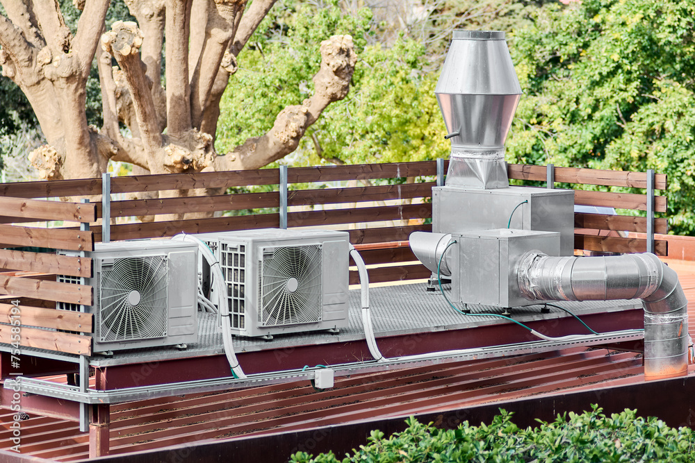 Outdoor air conditioning system on a roof with vegetation around it