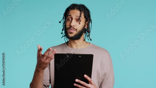 Public speaker reading from clipboard files, preparing discourse, rehearsing before doing speech. middle eastern orator telling monologue, isolated over studio background, camera B