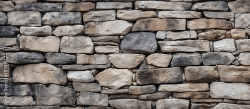 A sturdy stone wall, constructed using a combination of rocks and cement, stands tall as a reliable barrier. The rocks are tightly packed together, embedded in the hard cement,