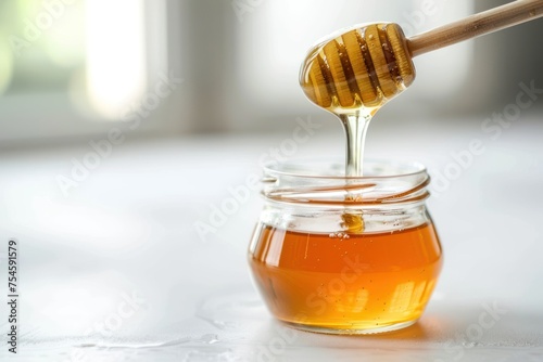 A jar of honey is poured out of a spoon. The honey is golden and thick, and it is dripping from the spoon. Concept of World Bee Day