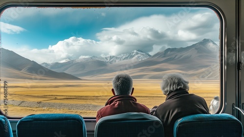 Para starszych osób siedzi w pociągi i patrzy na piękne góry za oknem © Artur