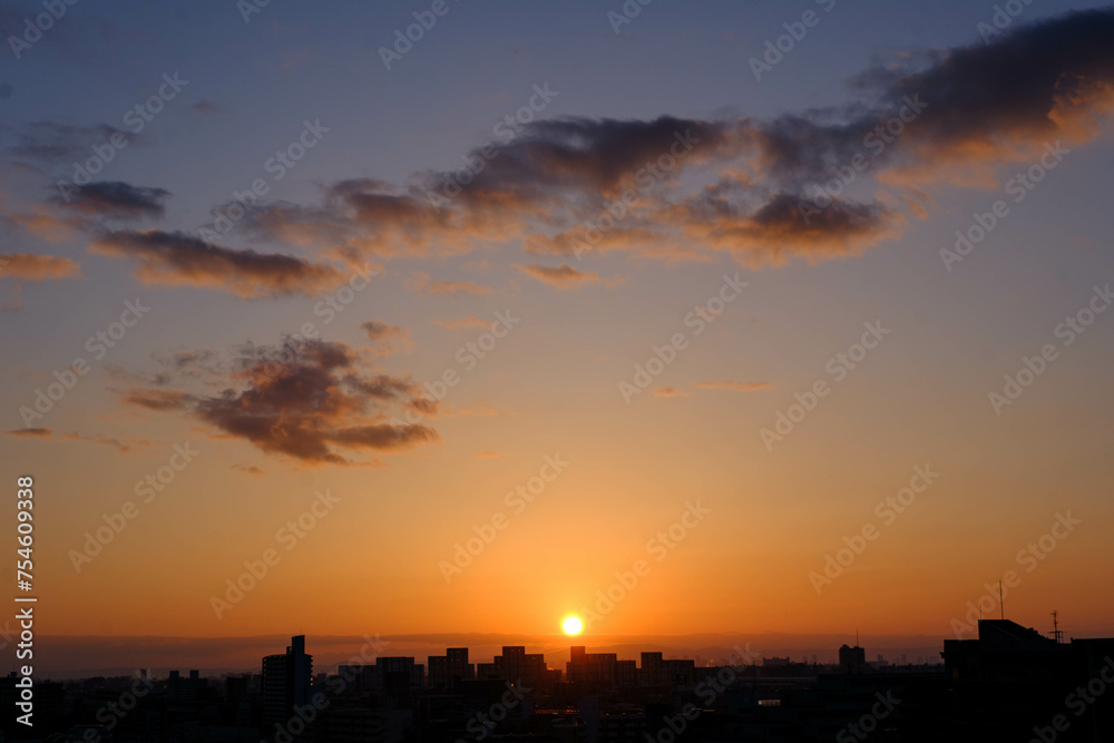 都市の夜明け。神戸市から芦屋大阪方面をのぞむ。生駒の山並みから朝日が昇る。都市のビルがシルエットで浮かぶ。 都市の夜明け。神戸市から芦屋大阪方面をのぞむ。生駒の山並みから朝日が昇る。都市のビルがシルエットで浮かぶ。